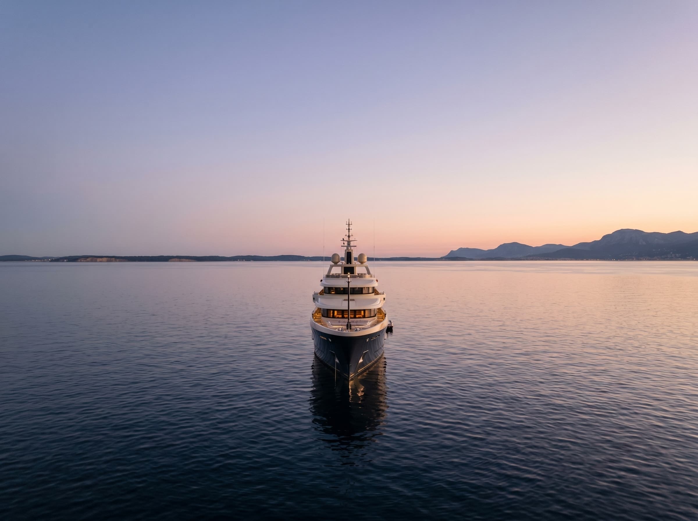 A dark-hulled motor yacht on calm Lake Ontario water at dusk