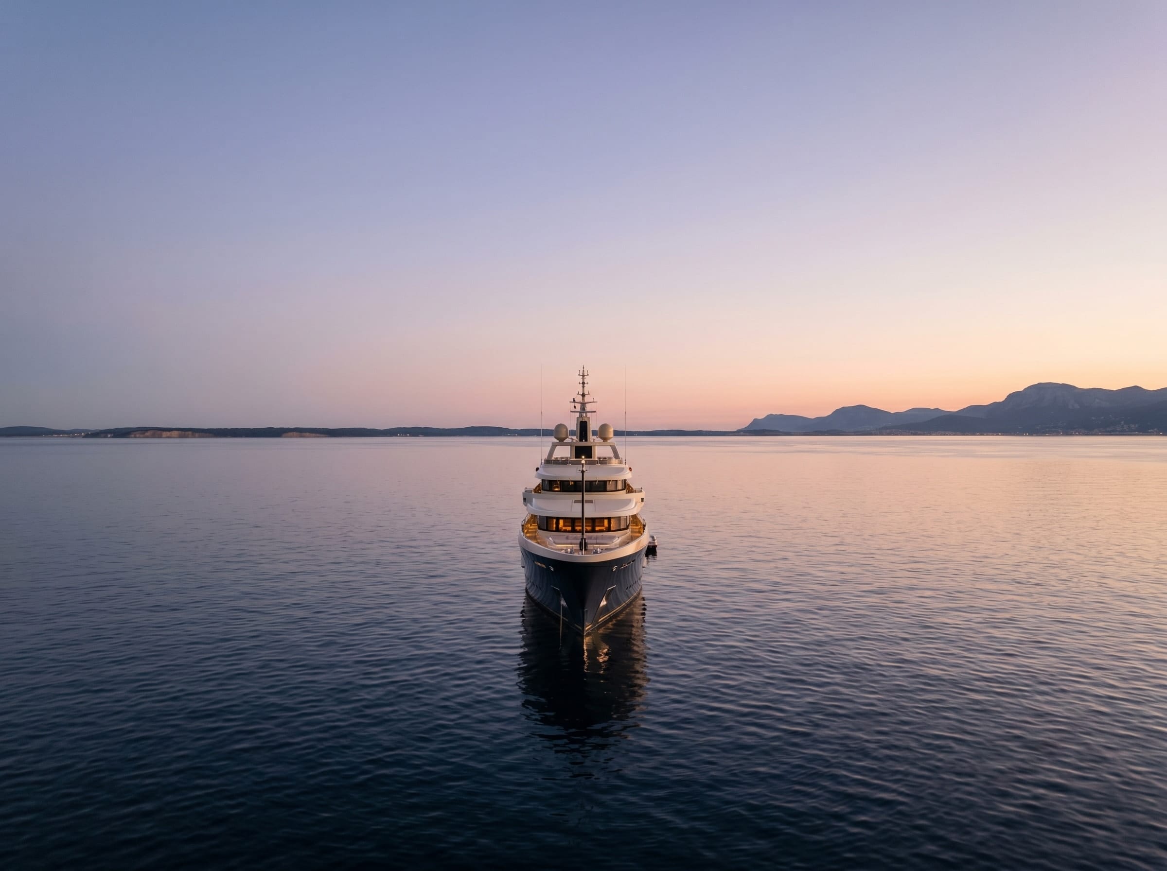 A dark-hulled motor yacht on calm Lake Ontario water at dusk